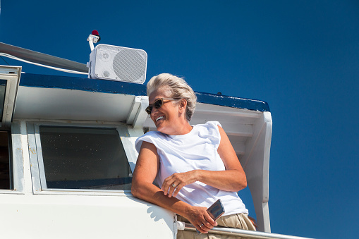 Senior women enjoys sailing on a boat. Sunny day. Clear blue sky on background.