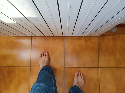 Barefoot indoors, mature man near the heater, High angle view