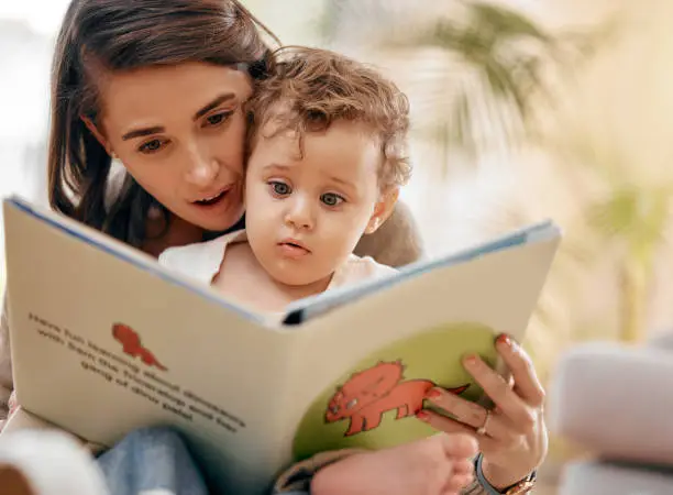 Photo of Shot of a mother reading a book to her son at home