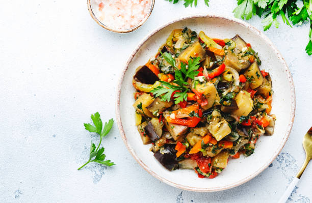 Vegetable stew, saute or caponata. Stewed eggplant with paprika, tomatoes, spices and herbs. White kitchen table background, top view, copy space