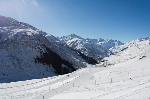 People walking down a ski slope at Nätschen above Andermatt, looking towards Hospeltal, Realp and Furka Pass in the Urseren Valley in Switzerland