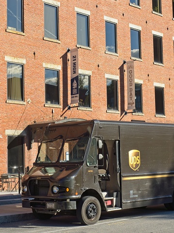 UPS truck delivers goods to the mill building district in downtown North Andover Massachusetts, September 2022. The brown step panel van is parked in front of business that are now housed in what was old textile mill buildings.