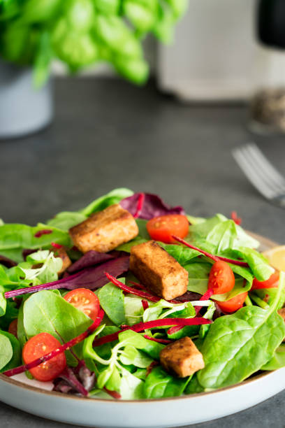 istock Healthy salad with roasted tempeh, cherry tomatos, beetroot straws, spinash and lettuce leaves on plate. Tempeh is fermented soy bean. Plant based protein. Healthy eating. Vertical card. Go vegan 1426346694