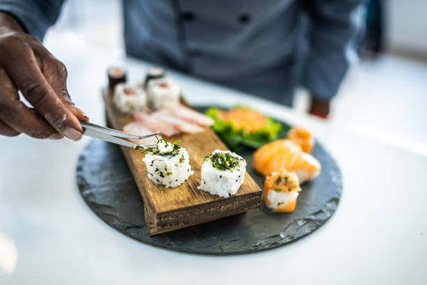 Chef's hands placing sushis in a plate