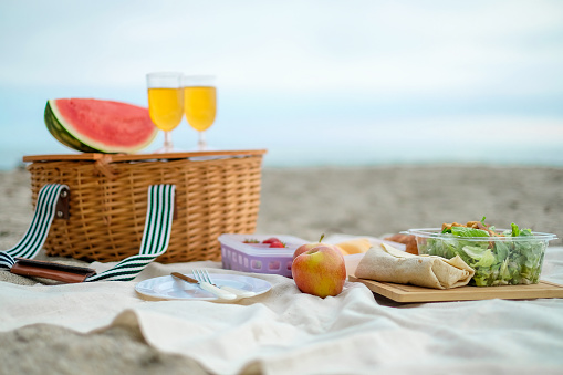 Picnic is set up on the beach. Wicker basket with food and drink for romantic picnic and relaxing. chill and good vibe.