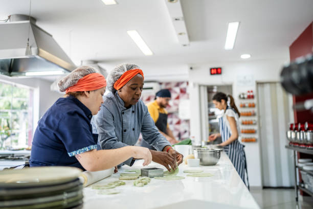 istock Teacher helping a student making pasta in a cooking class 1426350293