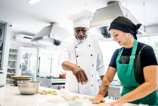 istock Senior chef helping a student making pasta in a cooking class 1426350770
