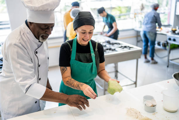 istock Senior chef helping a student making pasta in a cooking class 1426350919