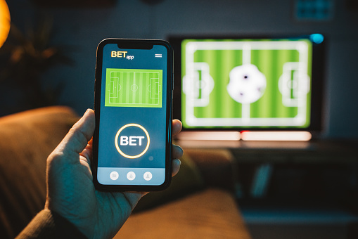 Close up of men's hand using smart phone for sports betting .