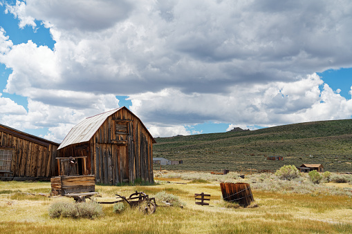 Rustic pole barn, in Paradise Valley, sits in beautigful pasture land backed by the Gallatin Mountains.  Beautiful morning sky has clouds and vivid blue.