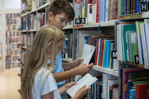 Young kids searching for books in the school library and having  fun