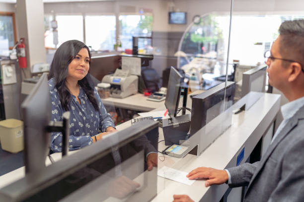 Cheerful bank teller assisting a customer stock photo