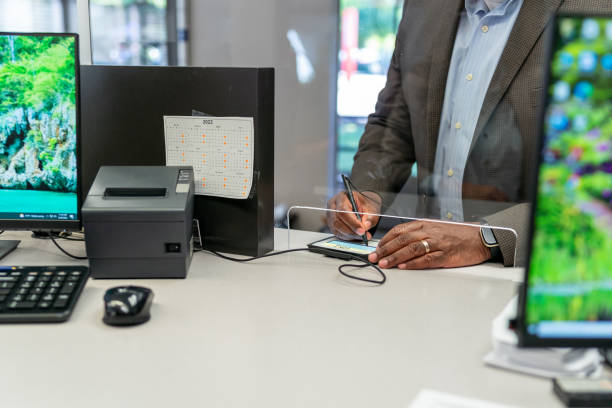 Customer signing after making credit card payment Close up shot of an unidentifiable black male customer providing electronic signature after paying medical bill at medical dental office or making deposit at the bank. bank teller stock pictures, royalty-free photos & images