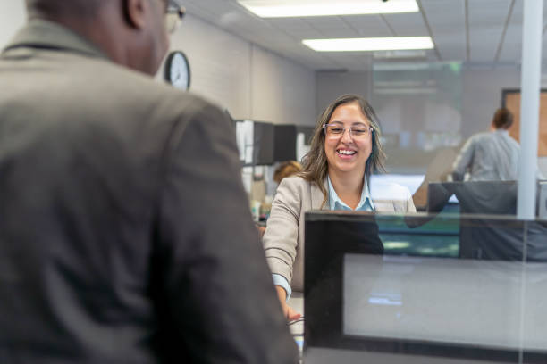 alegre representante de servicio al cliente saludando al cliente - mostrador en el banco fotografías e imágenes de stock