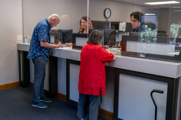 senior man and woman at business reception desk - bank bank teller customer banking imagens e fotografias de stock