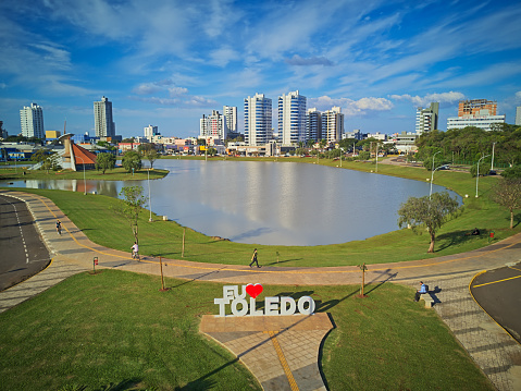 Aerial drone view of the lake and downtown of Toledo, Paraná, Brazil. Sunny day with blue sky and clouds in the sky.