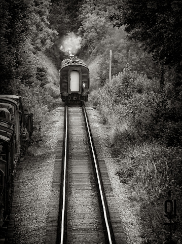 A steam locomotive travels away from us on the Watercress Line. The train departs, back in time.