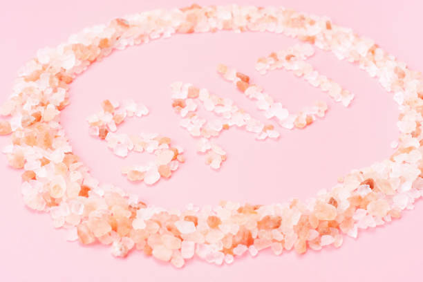 Inscription salt from himalayan salt close-up on a pink background.