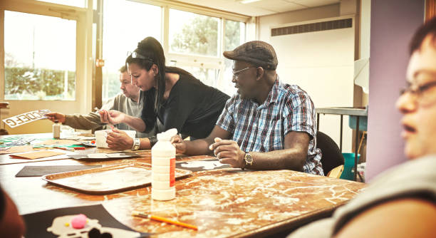 istock Artistic, creative people with learning disabilities in class at a community center. A black woman is teaching the group while the adults learn, listen and enjoy arts and crafts together. 1426386744