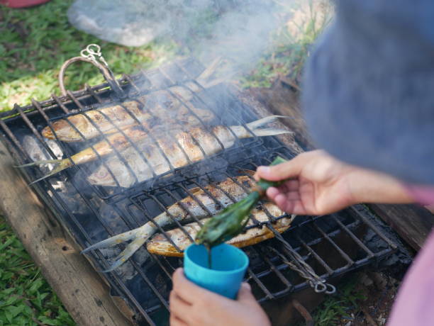 istock Process of grilling milkfish. Baking and roasting marinated milkfish on barbecue grill. Sea bass or grouper grilled over charcoal. 1426397783