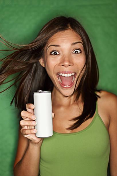 Woman drinking from blank can Woman drinking / showing blank can. Excited happy screaming girl holding energy drink or other drink. Asian / Caucasian female model on green background. See more woman drinking beer stock pictures, royalty-free photos & images