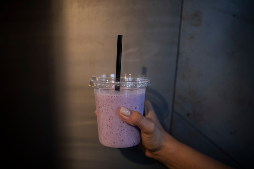 Close-up of female hand holding disposable cup with milkshake