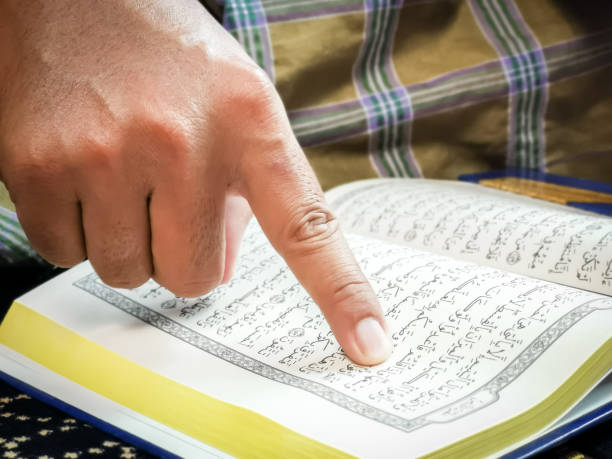 istock Close up man finger pointing on verse in Holy Al Quran. 1426414319