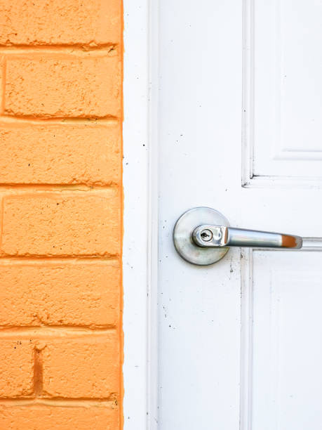 istock Modern white door with chrome door handle and orange wall bricks 1426424306