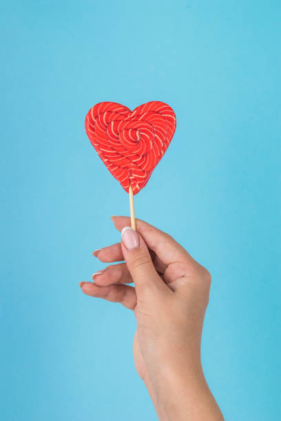 istock A girl's hand with a bright red candy on a blue background. 1426432181