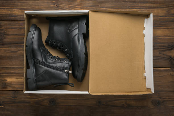 istock An open cardboard box with leather shoes on a wooden background. 1426432186