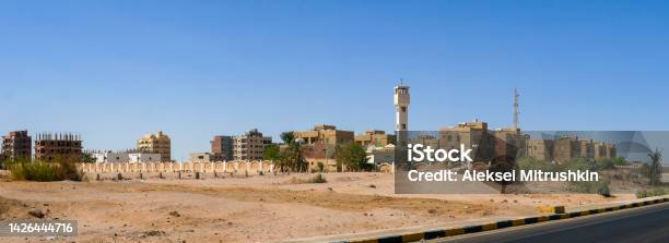 Panoramic View From The Road To The Low Houses Of Local Residents Surrounded By Desert And Palm Trees Against The Background Of A Blue Sky Copy Space Safaga Egypt Stock Photo - Download Image Now