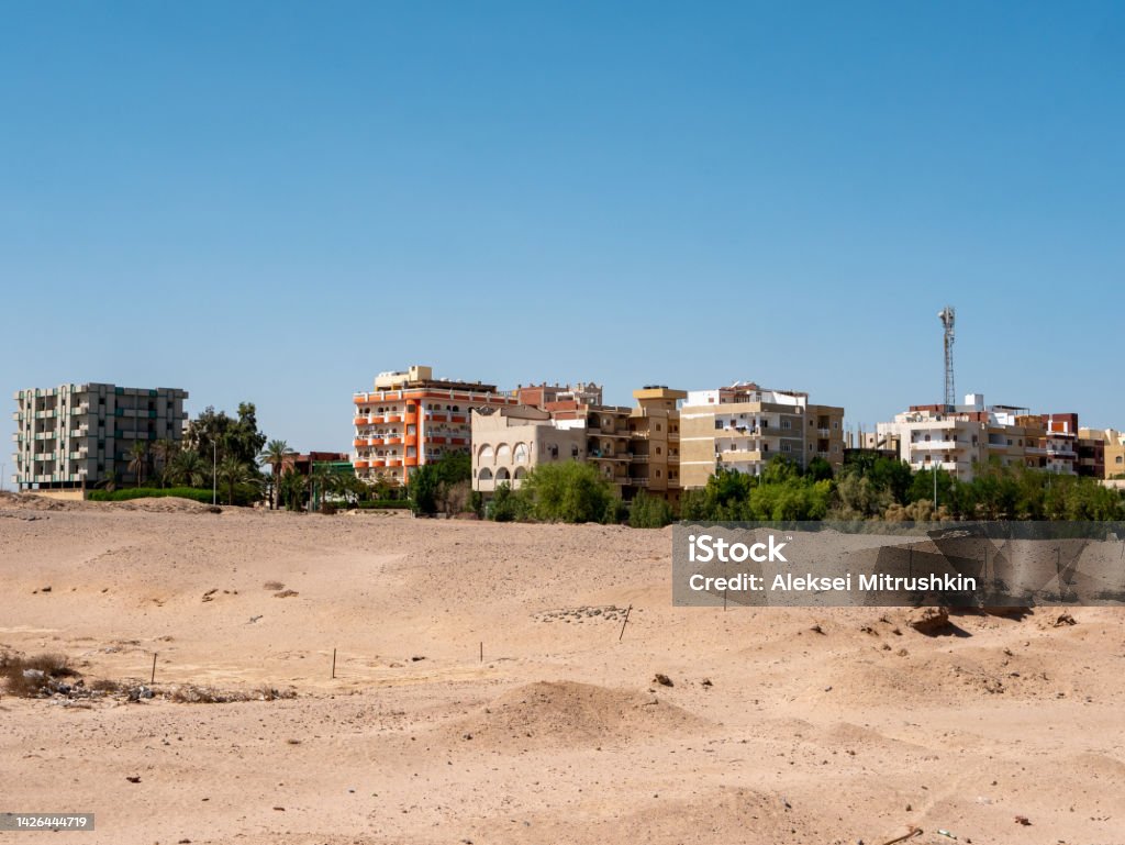 View of the houses of local residents surrounded by desert and palm trees against the backdrop of a blue sky. Copy space. Safaga, Egypt View of the houses of local residents surrounded by desert and palm trees against the backdrop of a blue sky. Copy space. Safaga, Egypt. Africa Stock Photo