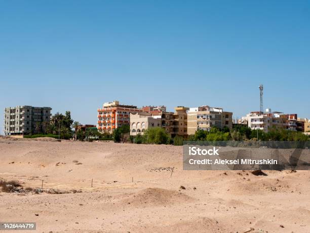 View Of The Houses Of Local Residents Surrounded By Desert And Palm Trees Against The Backdrop Of A Blue Sky Copy Space Safaga Egypt Stock Photo - Download Image Now
