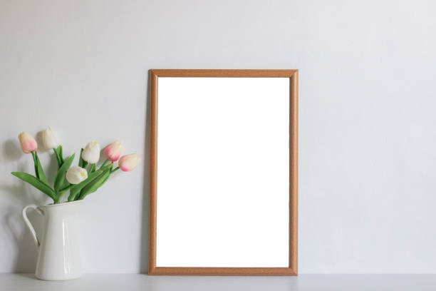 istock A wooden photo frame and tulips on white wall with natural light. 1426449246