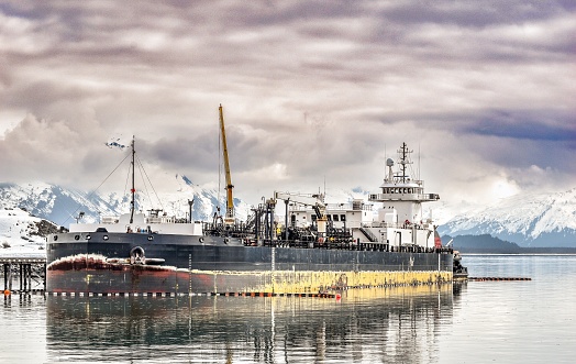 A fuel ship stands at the docks in Alaska. The stunning landscape and reflection gives this nautical vessel a sense of dominion over the weather.