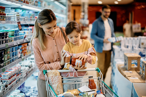 Happy mother with daughter shopping groceries in supermarket.
