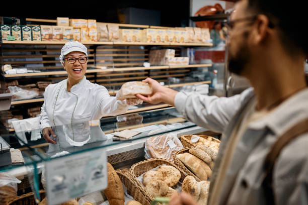 istock Happy supermarket baker serving male customer. 1426459432