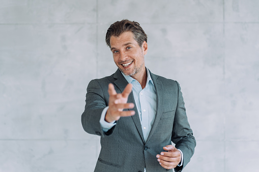 Handsome elegant male entrepreneur discussing while having a conference call in the office. Portrait of confident male employee looking at camera  talking on video call in the office. Businessman talking and gesturing against the camera.