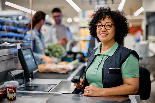 Portrait of happy female supermarket cashier looking at camera.