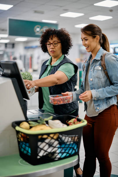 istock Supermarket worker assisting a buyer in using self-service till at checkout. 1426460177