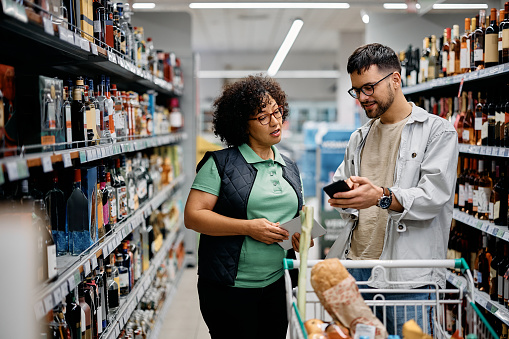 Supermarket worker assisting a buyer in using mobile app at the store.
