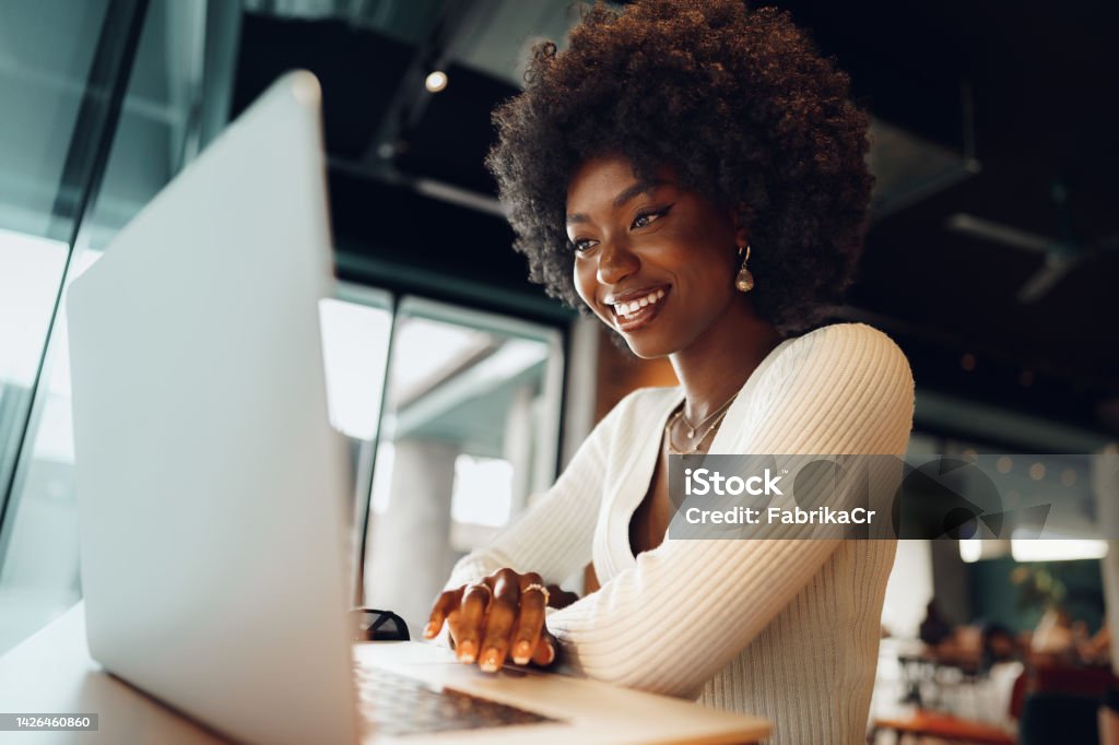 Smiling young african woman sitting with laptop in cafe Smiling young african woman sitting with laptop in cafe, portrait Laptop Stock Photo