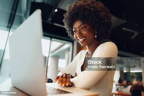 Smiling Young African Woman Sitting With Laptop In Cafe Stock Photo - Download Image Now