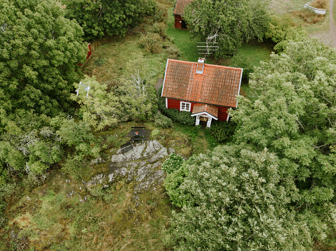 Drone point of view of red Swedish cottage in beautiful nature location.