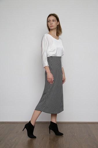Serie of studio photos of attractive young female model wearing elegant white silk satin blouse and jacquard midi skirt.