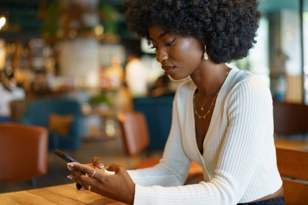 istock Young woman using mobile phone at coffee shop 1426466951