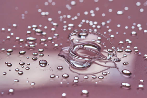 istock A large drop and splashes of micellar water on a pink background. 1426469149