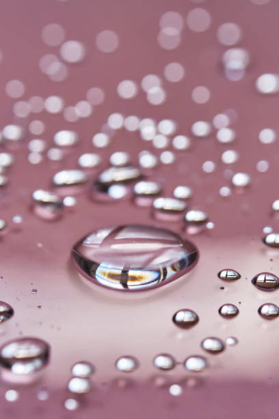 istock A large drop and splashes of micellar water on a pink background. 1426469510