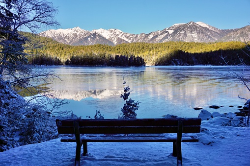Snow-capped mountains are reflected in the lake. Alpine mountains rise above the lake.