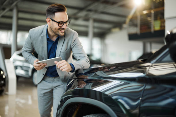 istock Happy car salesman working in a showroom. 1426470806
